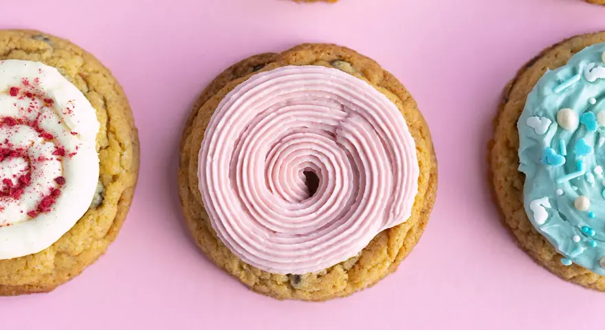 Galletas americanas decoradas con glaseado rosa, blanco con frambuesa y azul con chispas. ¡Una deliciosa receta para compartir!