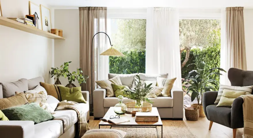 Salón con sofás, sillón, mesa de centro y alfombra de yute. La decoracion aesthetic se realza con cojines en tonos tierra y verdes, plantas y luz natural.