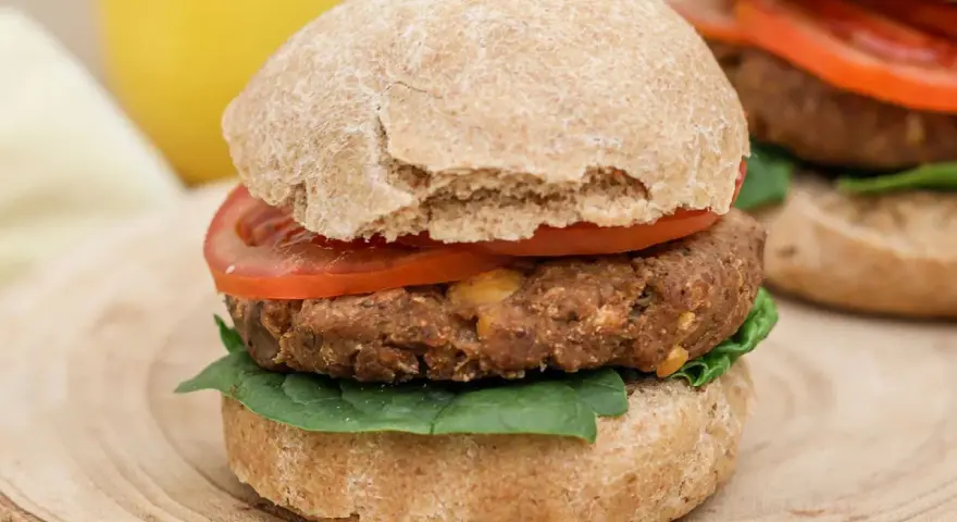 Hamburguesa de legumbres con pan integral, tomate y espinacas.
