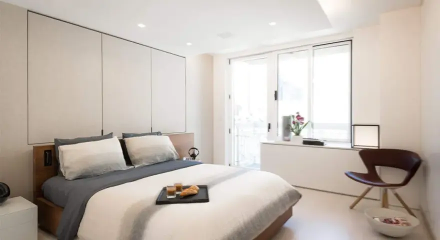 Camera da letto moderna con letto king-size, pannelli imbottiti e soffitto con faretti e strisce led controsoffitto che creano un'atmosfera rilassante.
