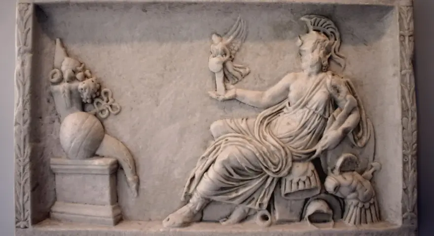 A marble relief depicting a seated figure, possibly a goddess, holding a winged victory. This scene reflects the rich tapestry of Roman paganism, with symbolic offerings and divine representation.