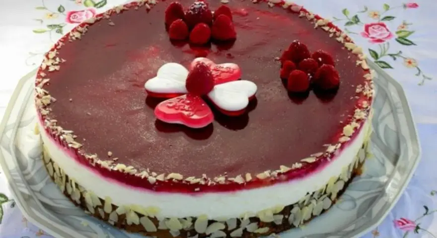 Himbeer Mohn Torte mit frischen Beeren und Herz-Gelees. Ein süßer Genuss für besondere Anlässe.