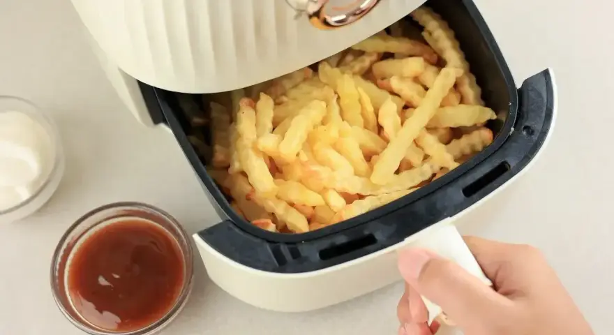 Air fryer co to? To urządzenie, które przygotuje chrupiące frytki bez nadmiaru tłuszczu. Obok sosy i majonez.