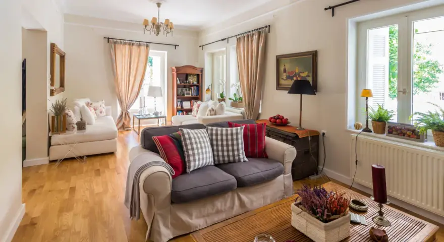 Przytulny salon w stylu angielskim z wygodnymi sofami, drewnianą podłogą i stylowymi dodatkami.