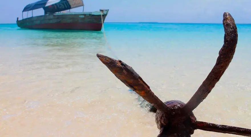 Kotwica na plaży, łódź na turkusowym morzu. Idealne miejsce na Zanzibar wycieczki fakultatywne.