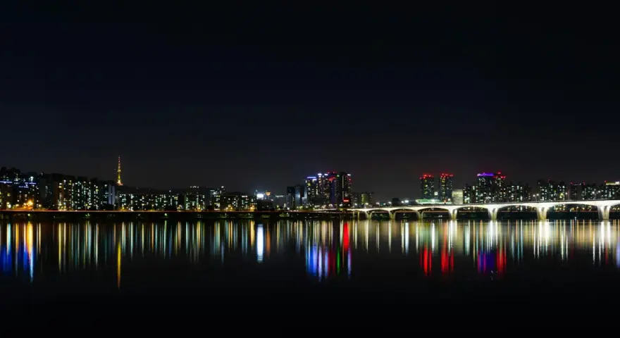 Nocny widok na Seul z rzeką Han, mostem i wieżą Namsan. Światła miasta odbijają się w wodzie, tworząc magiczny krajobraz. Itaewon tętni życiem.
