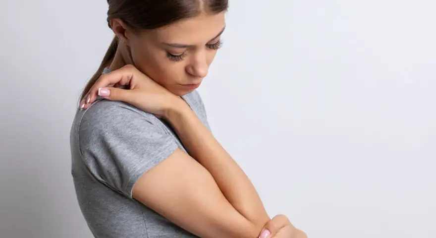 Mujer con dolor de codo, su piel con textura granulada se ve tensa.