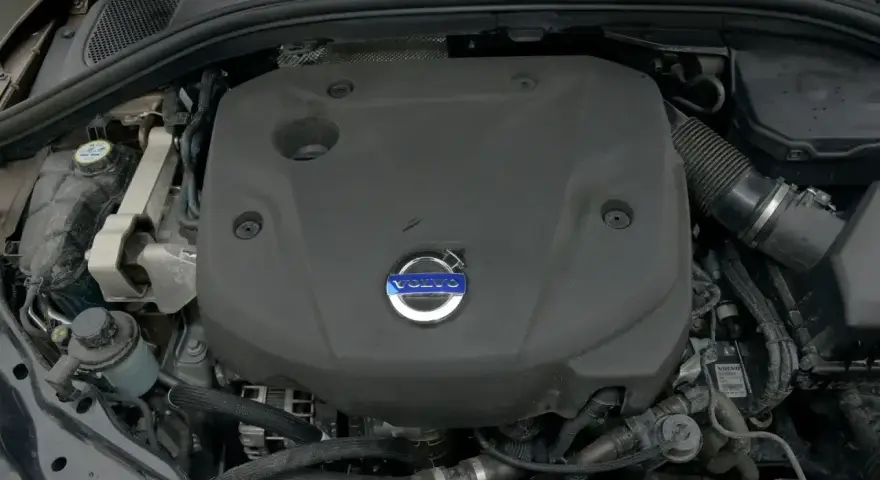 Silnik D4 Volvo pod czarną osłoną z niebieskim logo. Widać fragmenty przewodów i zbiornik płynu.