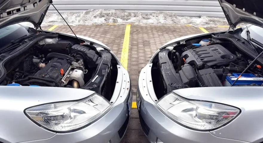 Dwa silniki samochodowe, jeden diesel, drugi benzyna, stoją obok siebie. Różnice w budowie są widoczne, choć oba napędzają auta.