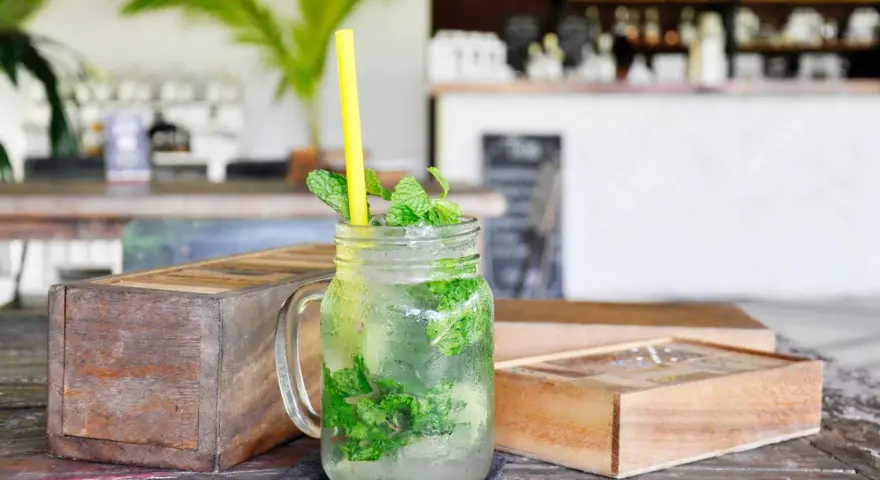 Erfrischender Mojito mit Minze und Eis in einem Glas. So trinkt man Rum an einem heißen Tag.