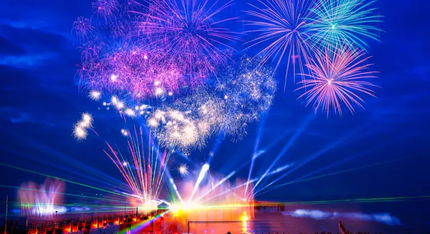 Spektakuläres Feuerwerk und Lichtshow an der Ostsee. Menschen feiern Silvester mit einer ausgelassenen Party am Strand.