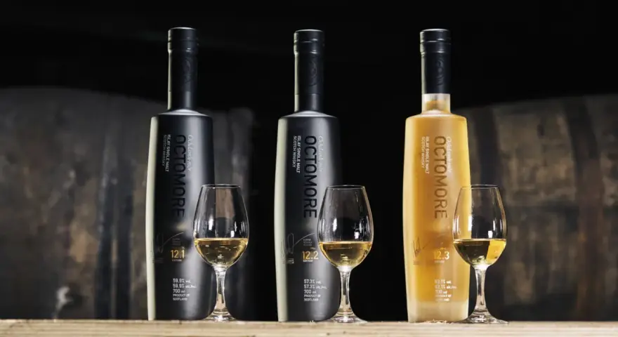 Trzy butelki Octomore, znanej z tego, że jest najbardziej dymna whisky, stoją obok kieliszków z bursztynowym płynem.