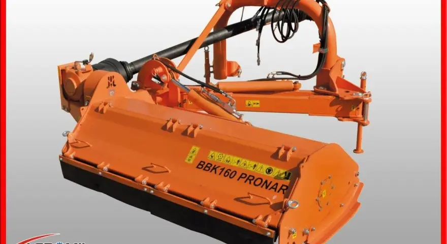 Pomarańczowa kosiarka tylno boczna BBK160 PRONAR z wałkiem WOM i elementami hydraulicznymi, gotowa do pracy w polu.