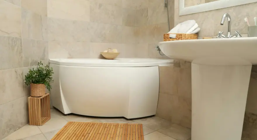 Ett badrum med hörnbadkar, handfat och en trämatta. Perfekt för liten toalett inspiration med naturliga material.