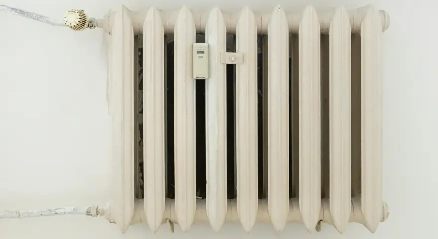 Biały grzejnik żeberkowy z termometrem i zaworem. Optymalna temperatura dla taryfy g12.