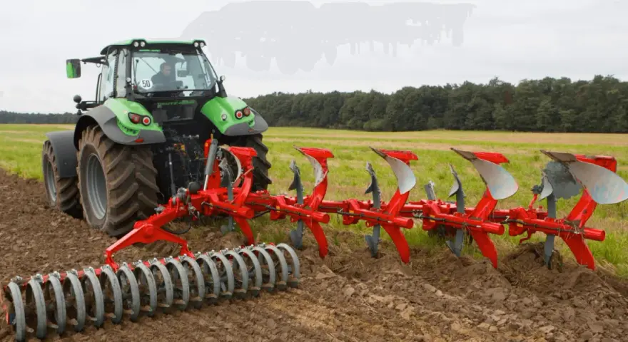 Zielony traktor z pługiem obrotowym pracuje na polu, przygotowując ziemię do siewu.