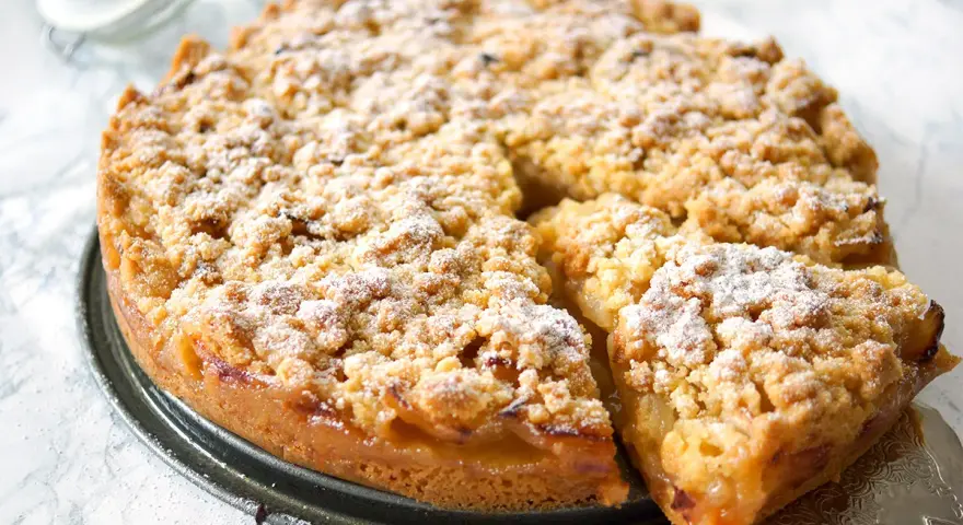 Ein goldbrauner Apfelkuchen mit Streuseln, bestäubt mit Puderzucker. Dieses Apfelkuchen Rezept sieht köstlich aus!