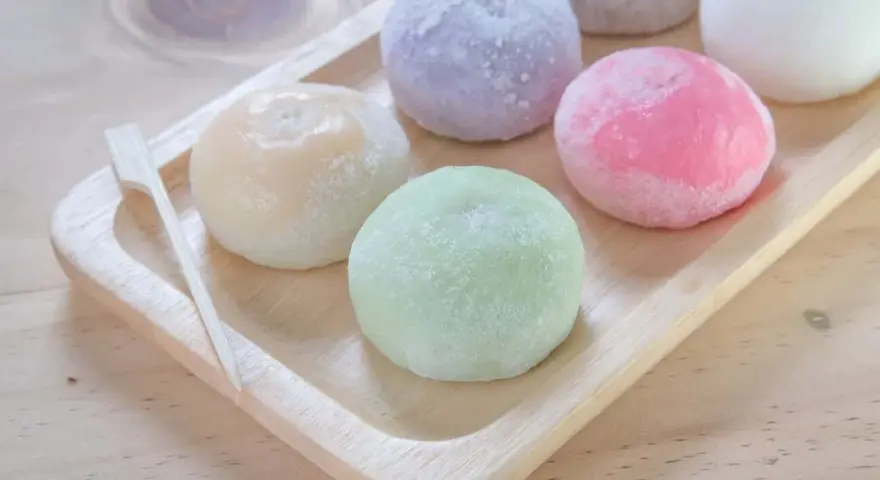 Kolorowe mochi, czyli japońskie ciastka ryżowe, na drewnianej tacy. Zastanawiasz się mochi co to? To pyszna, miękka przekąska!