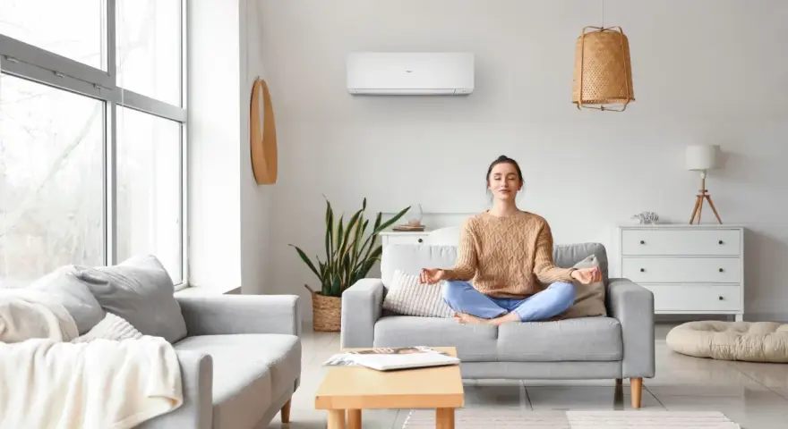Donna medita in un soggiorno confortevole, con un condizionatore d'aria inverter che garantisce un clima ideale per il relax.