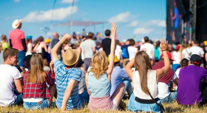 Widok zza pleców na tłum ludzi na jednym z największych festiwali muzycznych w Polsce. Słońce, niebo i dobra zabawa.