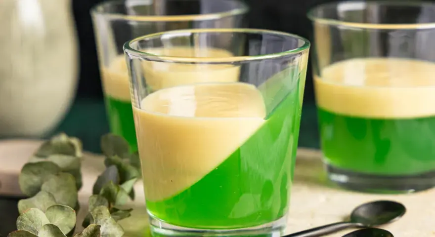 Zwei Schichten Wackelpudding, grün und gelb, in Gläsern. Perfekt, um Wackelpudding selber machen zu lernen und zu genießen.