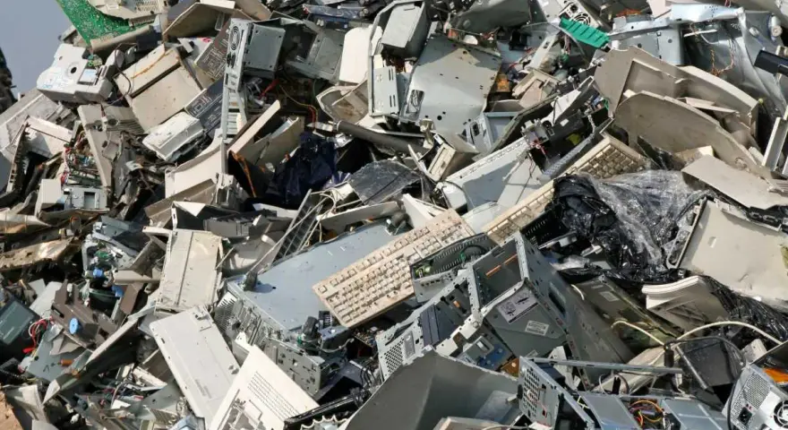 Góra starych komputerów, monitorów i klawiatur. To widok na odpady przemysłowe, które czekają na recykling.