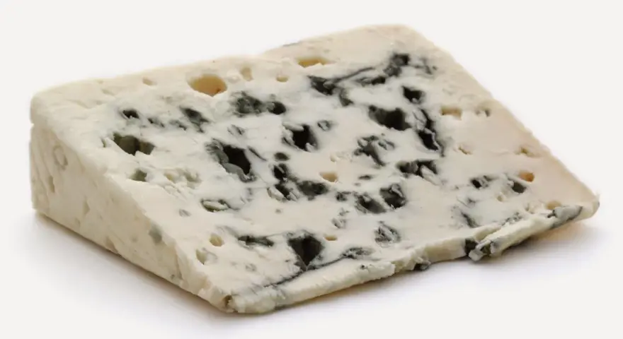 Un trozo de queso azul con vetas oscuras, un queso que huele mal pero es delicioso.
