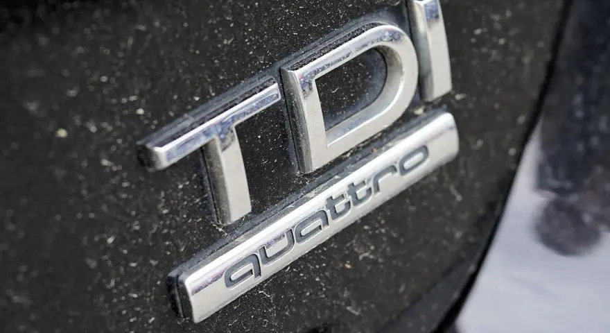 Emblemat TDI Quattro na zakurzonym czarnym lakierze. Zastanawiasz się, audi q5 2.0 tdi ile oleju?