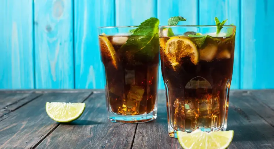 Dwa orzeźwiające drinki z rumem, lodem, limonką i miętą na drewnianym blacie. Idealny dobry drink z rumem na upalne dni.