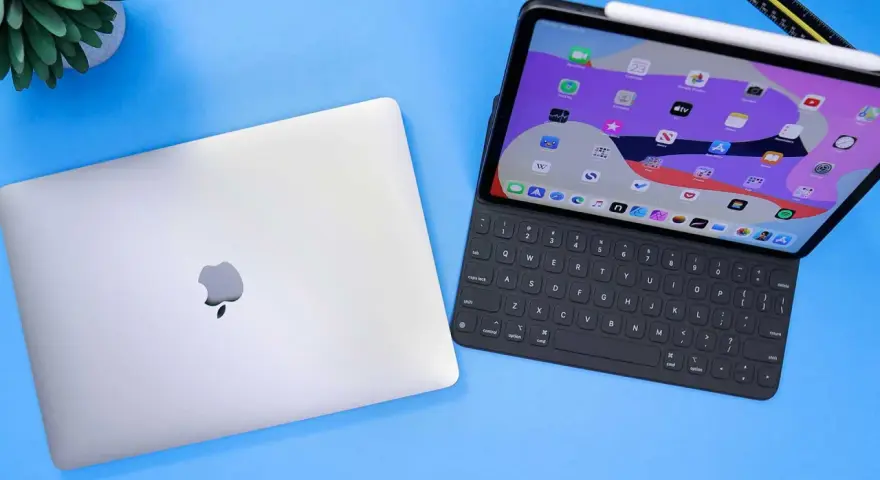 Geschlossenes MacBook neben einem geöffneten iPad Pro mit Tastatur und Apple Pencil.