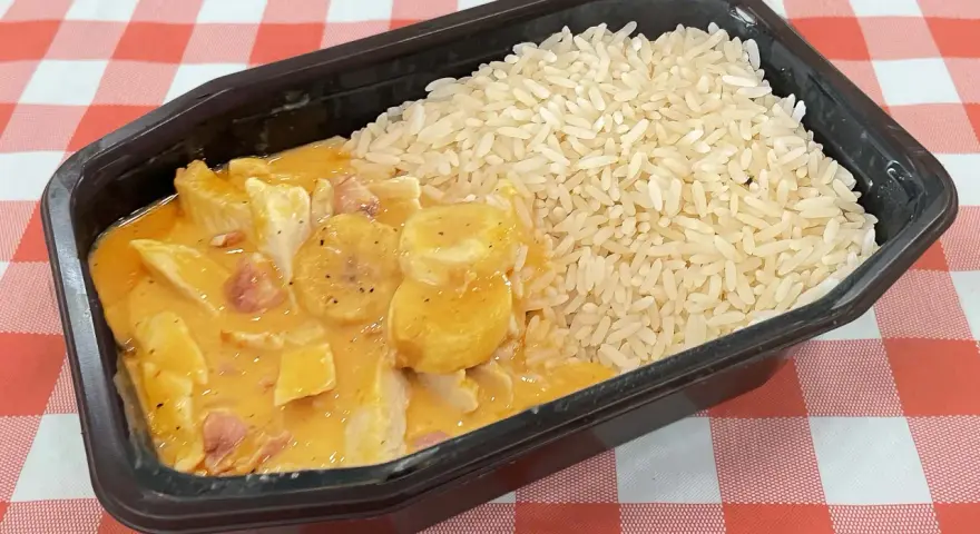 En portion flygande jacob med ris i en svart plastbehållare, serverad på en rödvitrutig duk.