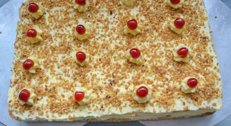 Rechteckiger Frankfurter Kranz Kuchen, bestreut mit gehackten Nüssen und verziert mit Sahnetuffs und Kirschen. Sally liebt diese Schnitten!