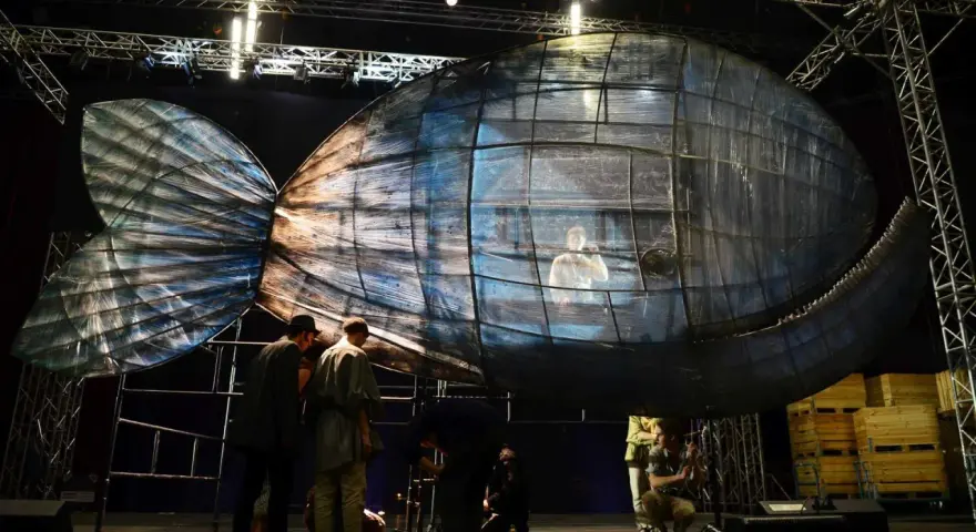 Scena teatralna z wielką, szklaną rybą, w której siedzi człowiek. To może być cud Jonasza.