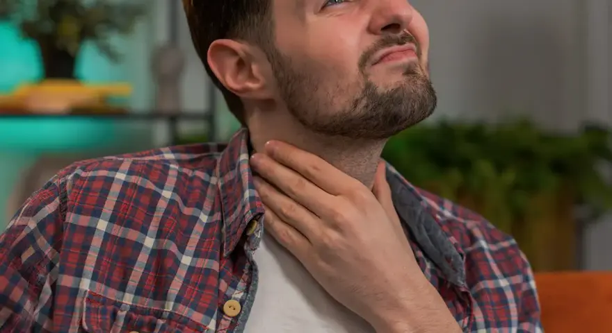 Mann mit Hand am Hals, besorgt über die Lebenserwartung nach Kehlkopfentfernung.