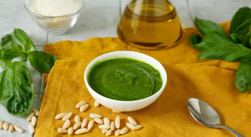 Una ciotola di pesto fresco, pinoli, basilico, parmigiano e olio d'oliva, ingredienti perfetti per una deliziosa pasta al pesto.