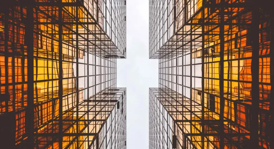 Looking up between four golden glass buildings, the architecture forms a cross shape, resembling a modern church.