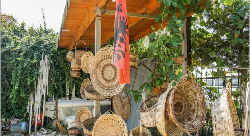 Wiele koszy z wikliny wisi pod zadaszeniem, obok albańskiej flagi. Czy Albania jest bezpieczna dla kobiet? Tak, to piękny kraj.
