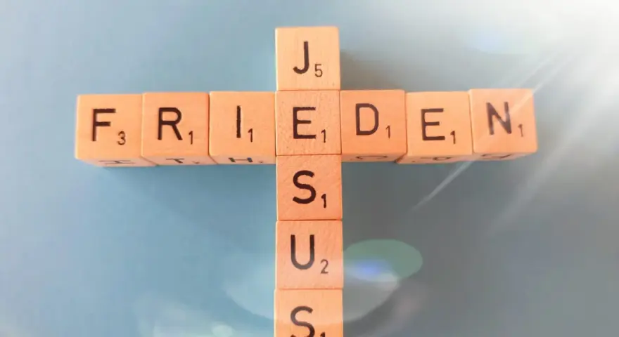Holzbuchstaben bilden ein Kreuz mit den Wörtern "FRIEDEN" und "JESUS". Wie in Jesaja 43,2 versprochen, bringt Jesus Frieden.
