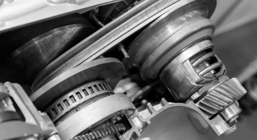Zbliżenie na mechanizm bezstopniowej skrzyni biegów z widocznym pasem i kołami pasowymi.