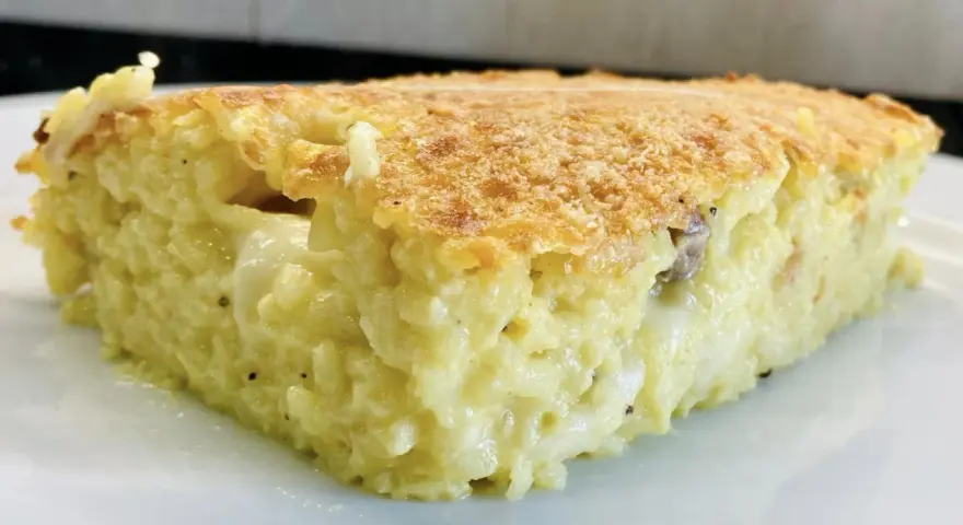 Una fetta di timballo di riso dorato e filante, con un ripieno cremoso e invitante.