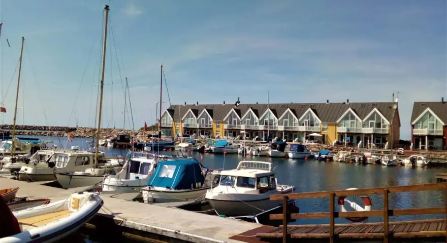 Port z łodziami i domkami w tle. Planujesz podróż rowerem na Bornholm? Koszty mogą być różne, ale widok jest wart każdej ceny.