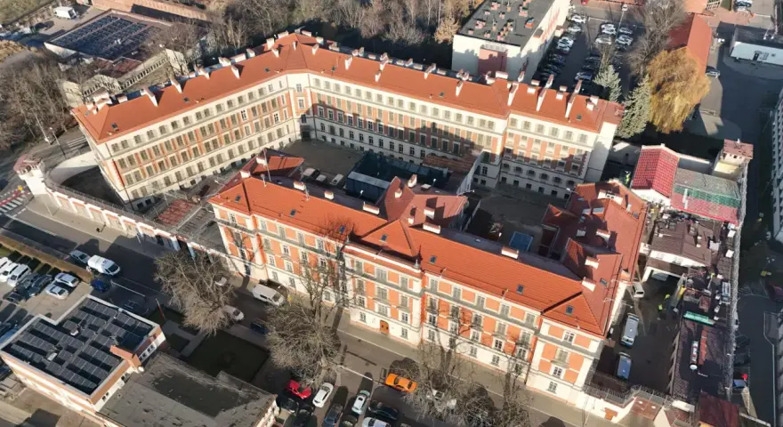 Widok z lotu ptaka na budynki więzienia aś montelupich. Czerwone dachy, białe fasady, dziedziniec z samochodami i drzewami.