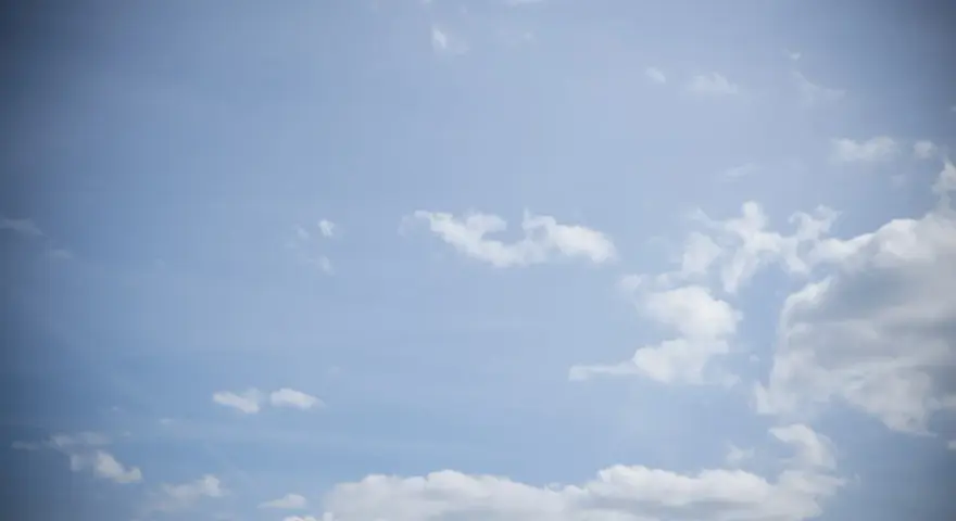 Jasne niebo z chmurami, efekt winietowania przyciemnia brzegi kadru, tworząc wrażenie głębi.