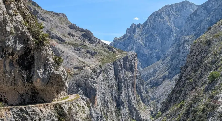 Wąska ścieżka wzdłuż skalnej ściany, część szlaku Ruta del Cares, prowadzi przez surowe, górskie krajobrazy.