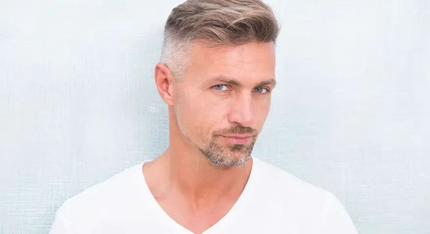 Hombre con barba corta y cabello peinado, luciendo un estilo moderno. Decidió dejarse perilla para un look más definido.