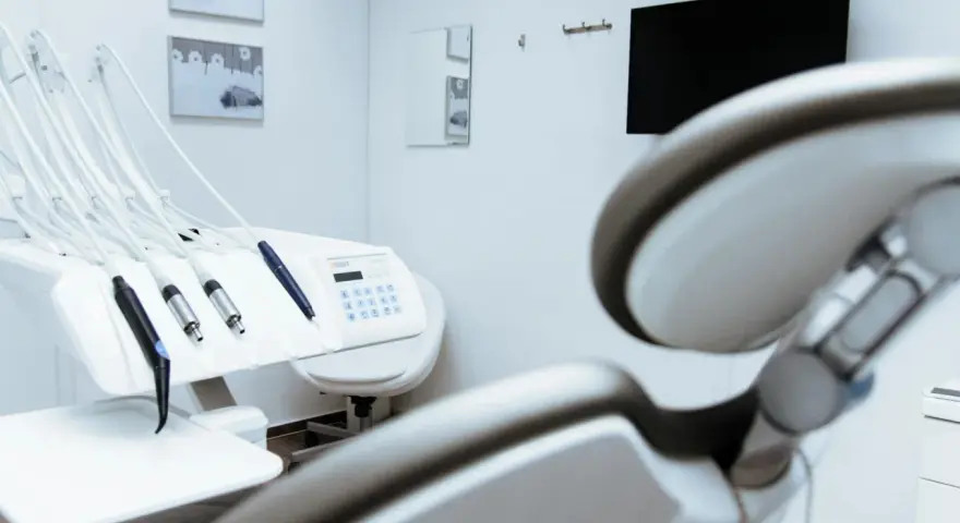 Gabinet stomatologiczny z fotelem i narzędziami. W tle monitor i lustro. Czystość i sterylność, jak po użyciu środka z chlorheksydyny diglukonianem.