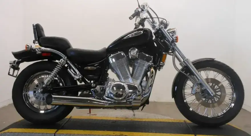 Czarny motocykl Suzuki Intruder 1400 z chromowanymi elementami, siedzeniem pasażera i bagażnikiem.
