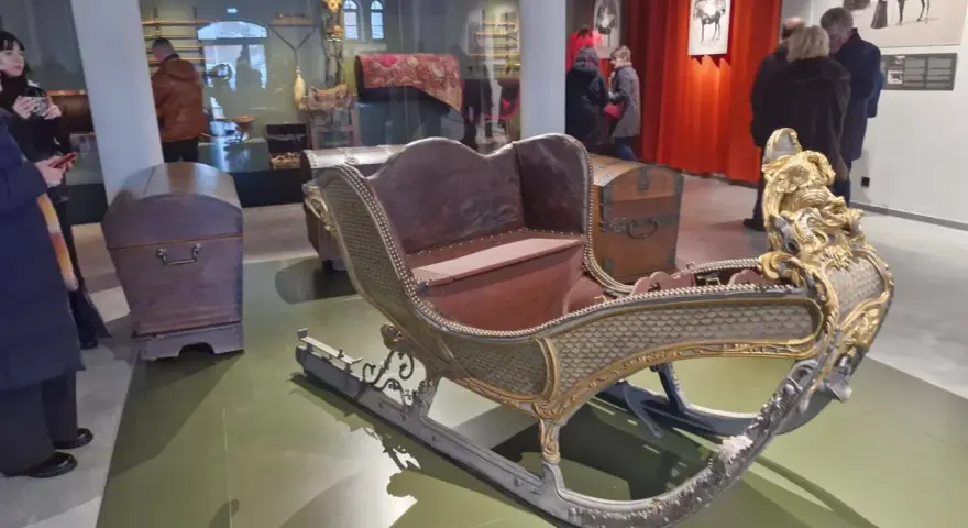 Złota, zdobiona sanie w muzeum tradycji szlacheckiej w Waplewie Wielkim. Obok skrzynie.