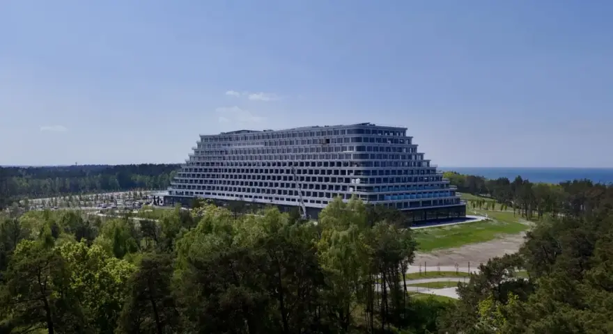 Nowoczesny hotel Gołębiewski Pobierowo w kształcie tarasowym, otoczony lasem, z widokiem na morze.