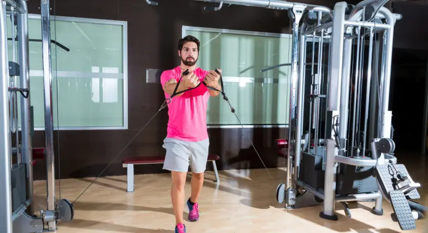 Man tränar bröstmusklerna med cable flyes i ett modernt gym.